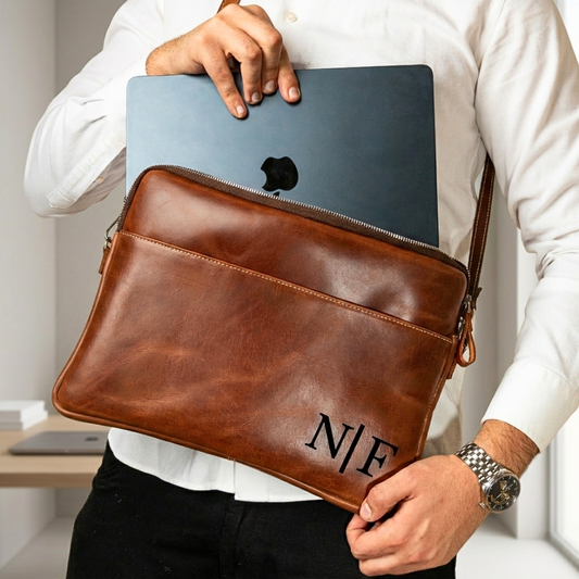 Man placing a 13-inch MacBook into a personalized chestnut leather laptop bag