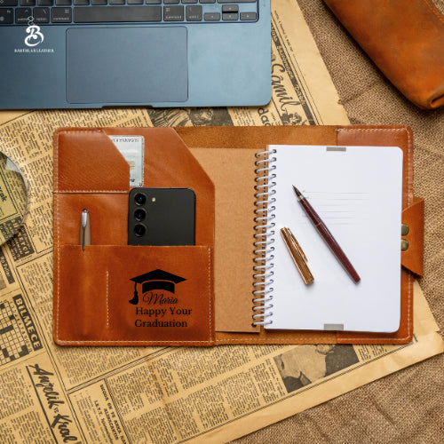 Open chestnut A5 portfolio with graduation monogram and notebook