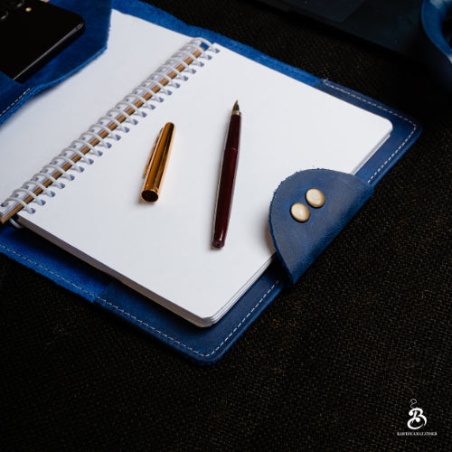 Open blue leather portfolio with spiral notebook and pens