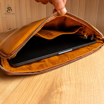 Open camel leather laptop bag showing device compartment and zip pocket