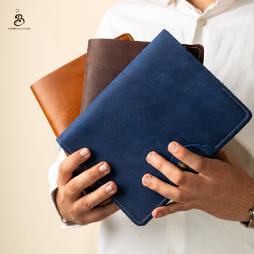 Person holding blue, chestnut, and dark brown A5 leather portfolios