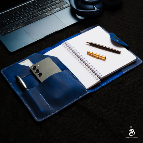 Blue A5 portfolio open beside a laptop and headphones