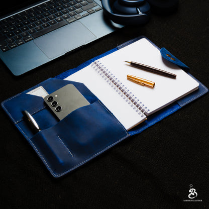 Blue A5 portfolio open beside a laptop and headphones