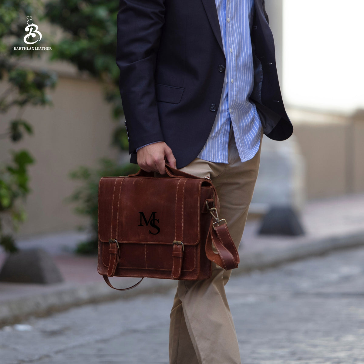 Man carrying a monogrammed chestnut leather briefcase outdoors