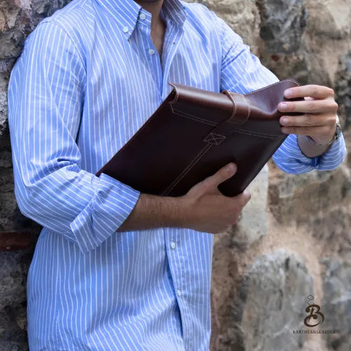 Man opening a brown leather iPad sleeve outdoors
