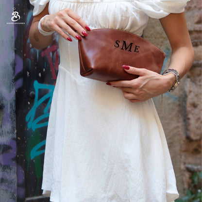 Woman carrying a brown leather makeup pouch with SME initials
